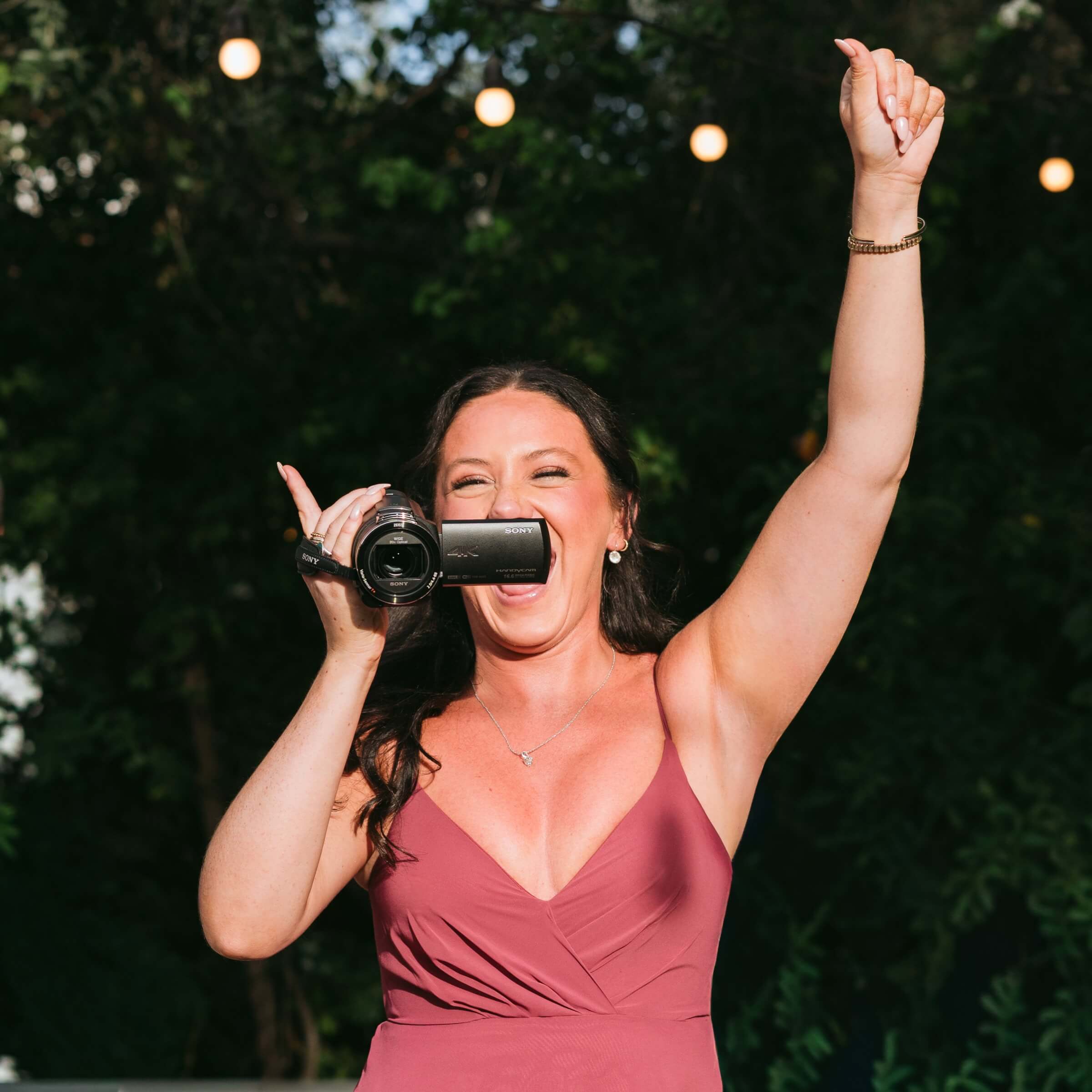 Wedding guest smiling and filming with a Sony camcorder at a reception