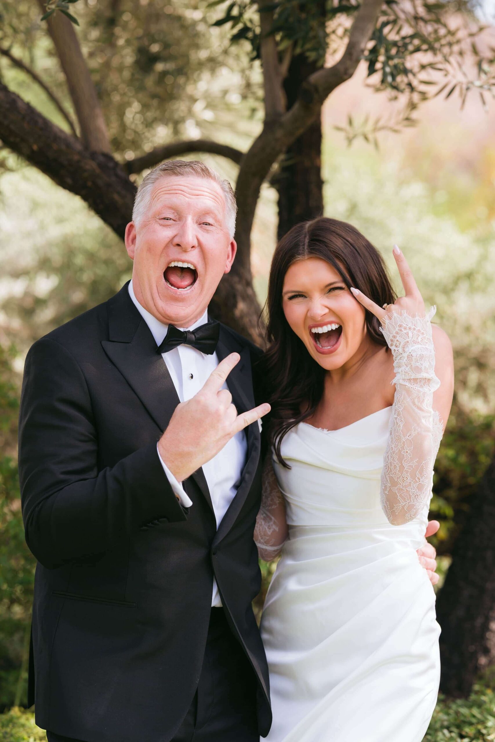 Bride laughing with her father during a candid outdoor wedding portrait