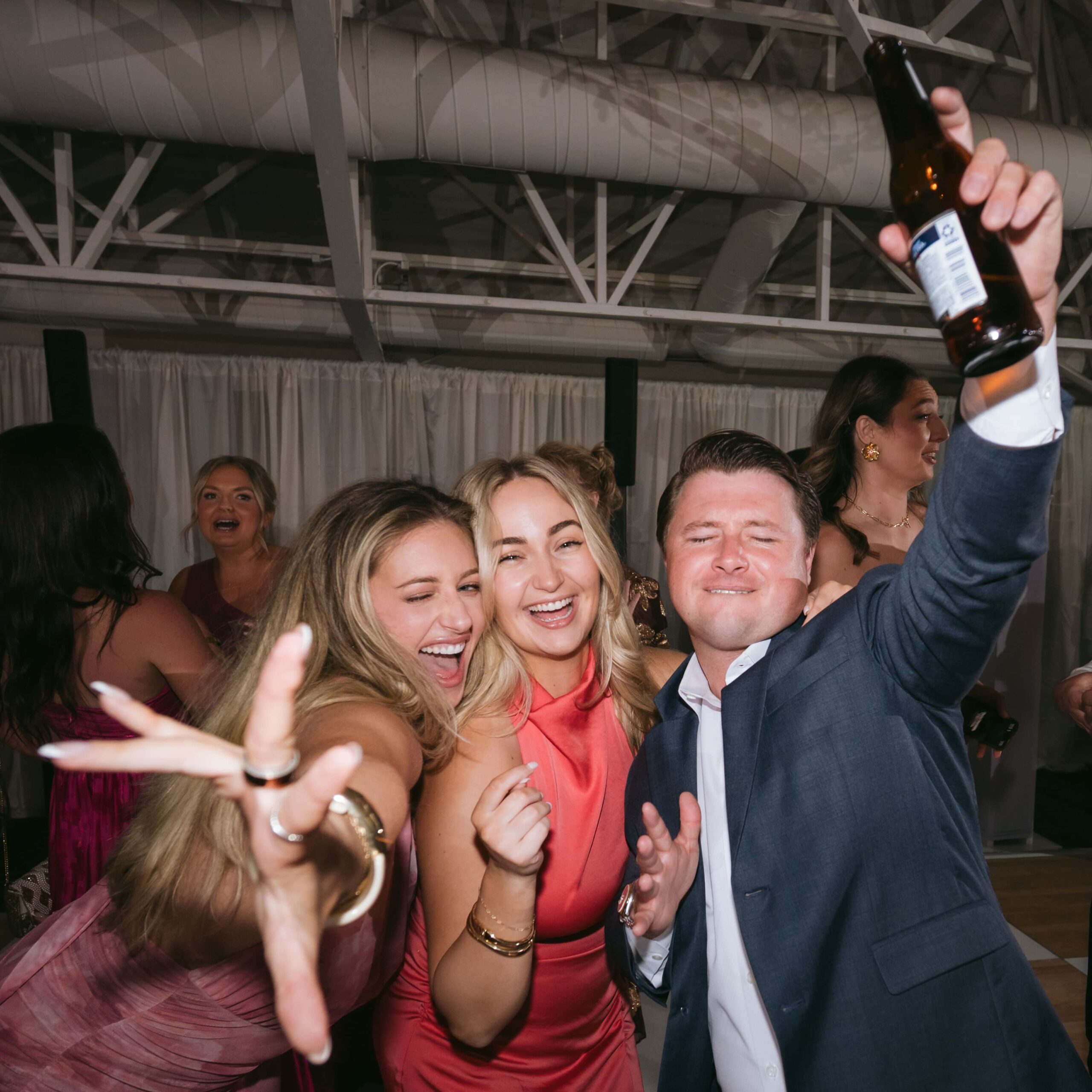 Wedding guests laughing and celebrating together on the dance floor during a reception