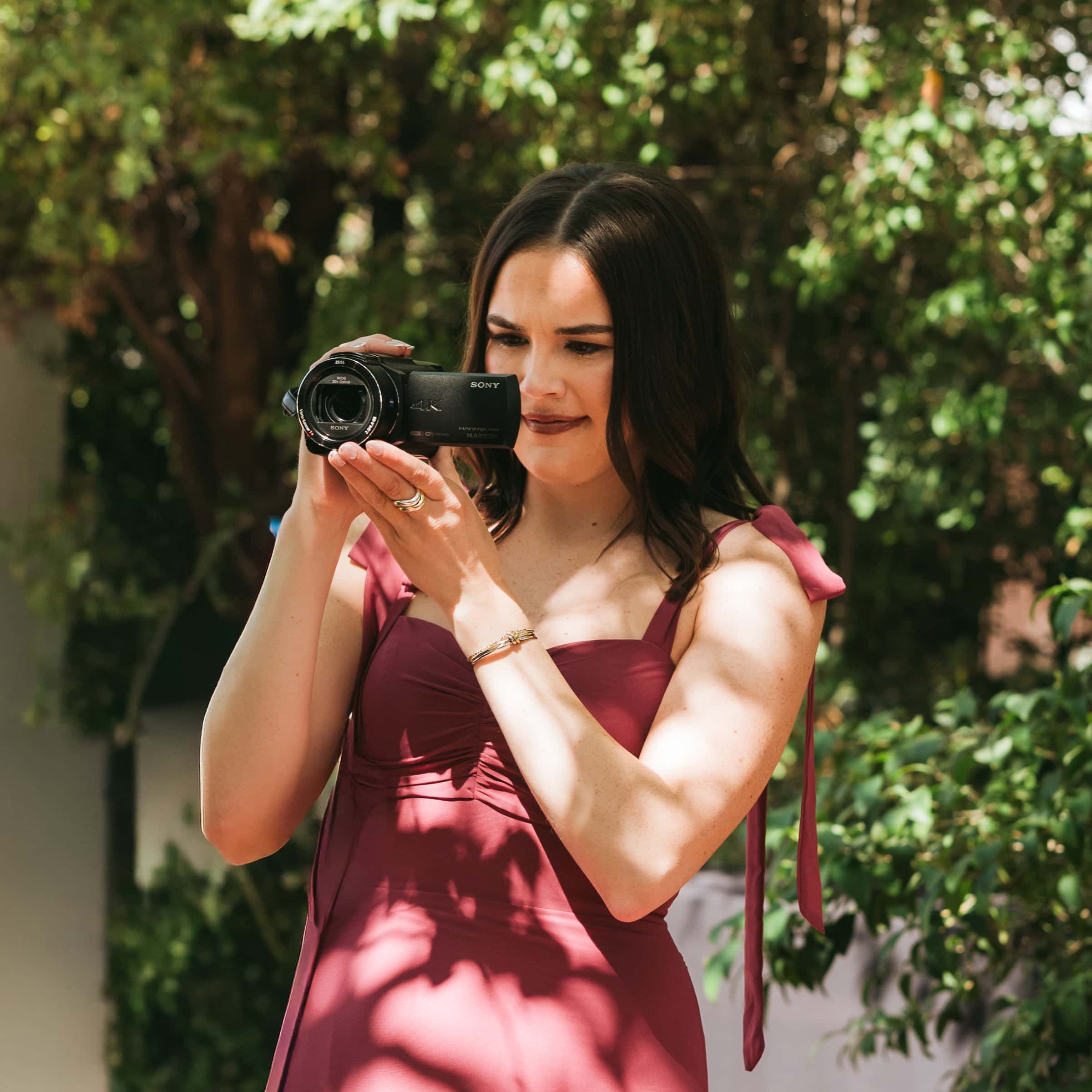 Wedding guest filming with a handheld Sony camcorder during an outdoor wedding